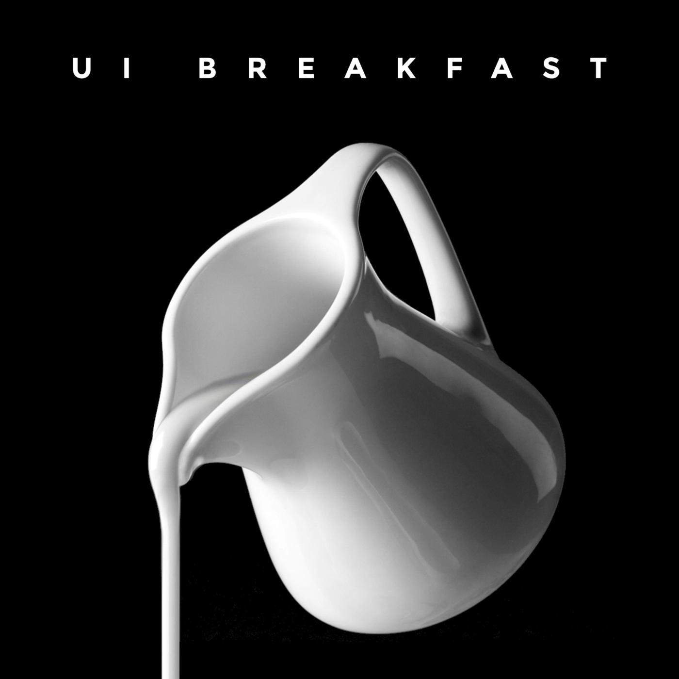 A white, ceramic jug pours milk out on a black background.